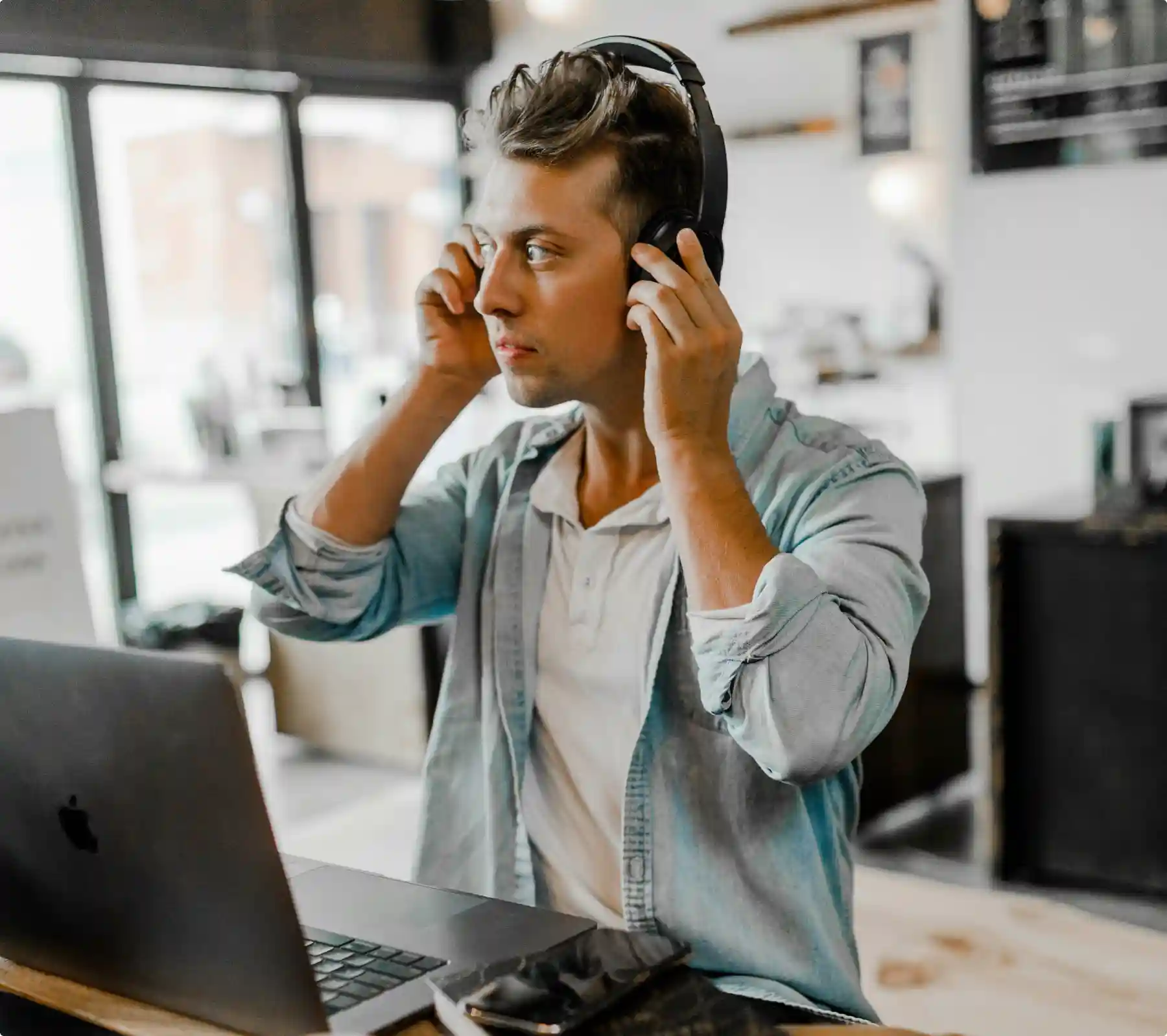 Person wearing headphones working at a laptop in a shared workspace